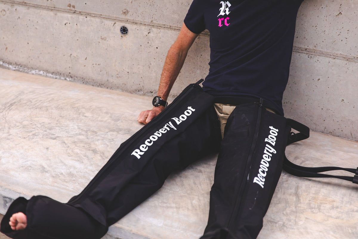 Athlete using air compression recovery boots after training to support leg recovery and reduce post-exercise muscle soreness