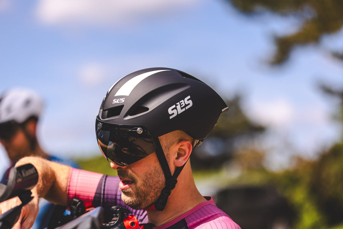 Triathlete wearing an SLS3 cycling helmet and sunglasses during an outdoor bike ride.