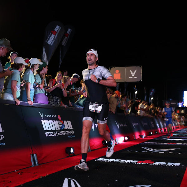 A man wearing a tri suit sprinting on a red carpet under the night sky