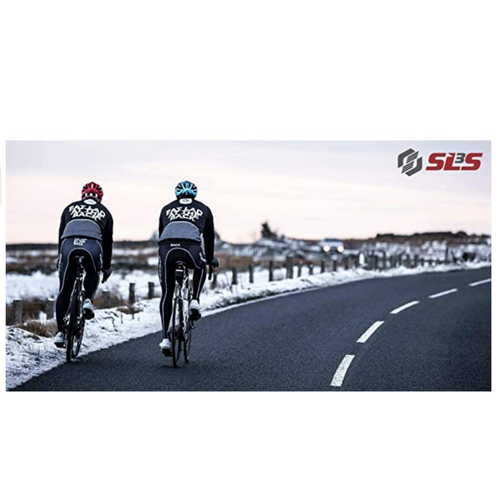 Two cyclists riding on an empty road with snow-covered fields