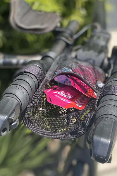 Close-up of a bicycle handlebar with a small black mesh pouch containing packets