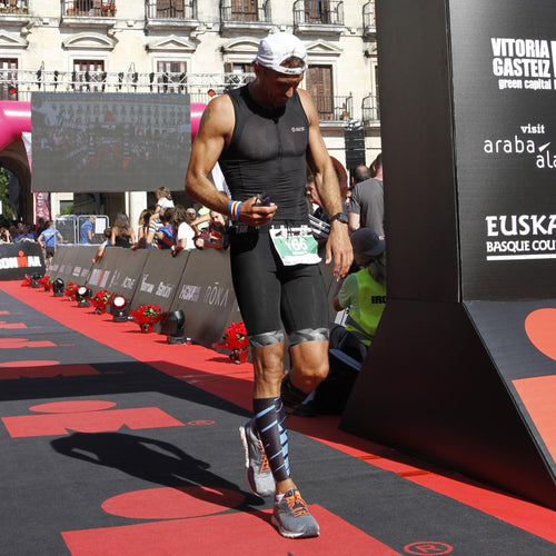 An athlete in a black top and shorts walking on a red carpet at a finish line