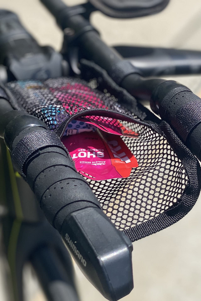Close-up of a bicycle handlebar with a black mesh pouch resting on top