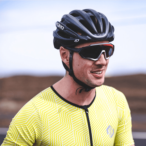 A man in a yellow top, black helmet, wearing sunglasses