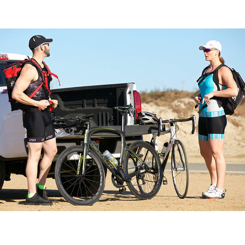 Two cyclists, a man and a woman, wearing running caps, standing beside their bikes