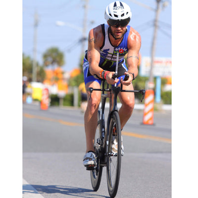 A person wearing a white aero triathlon helmet riding a bicycle