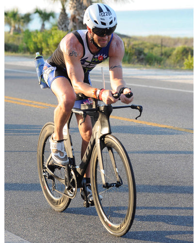 A person wearing a white triathlon helmet riding a bike