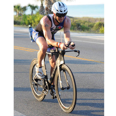 A person wearing a white triathlon helmet riding a bike