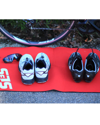 Pairs of shoes and a sunglass resting on a transition mat nearby a bicycle