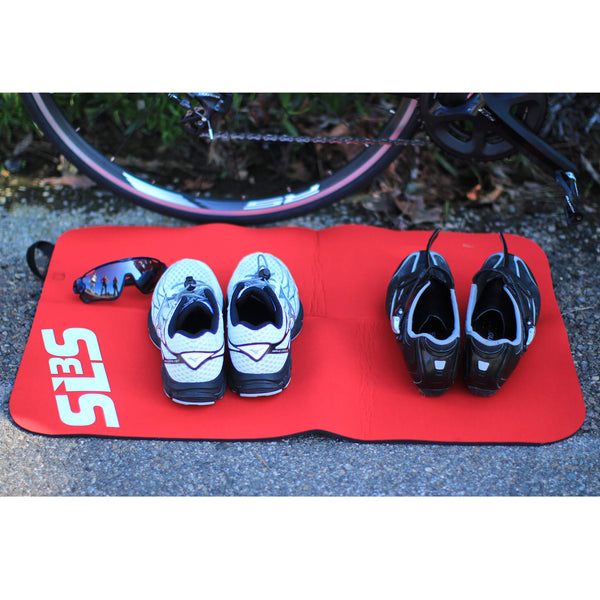 Pairs of shoes and a sunglass resting on a transition mat nearby a bicycle