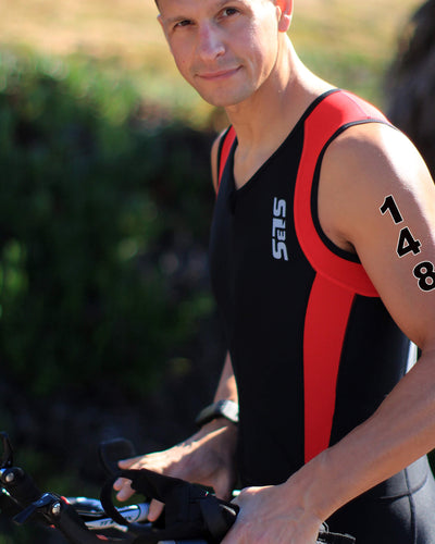 A person in a black and red tank top holding a bicycle