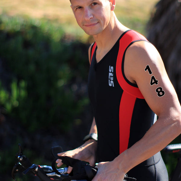 A person in a black and red tank top holding a bicycle