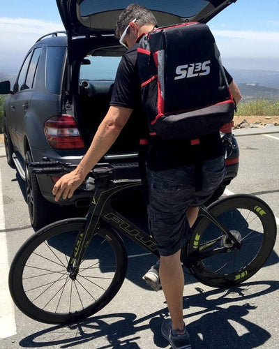 A person wearing a backpack with a bicycle in the back of his car