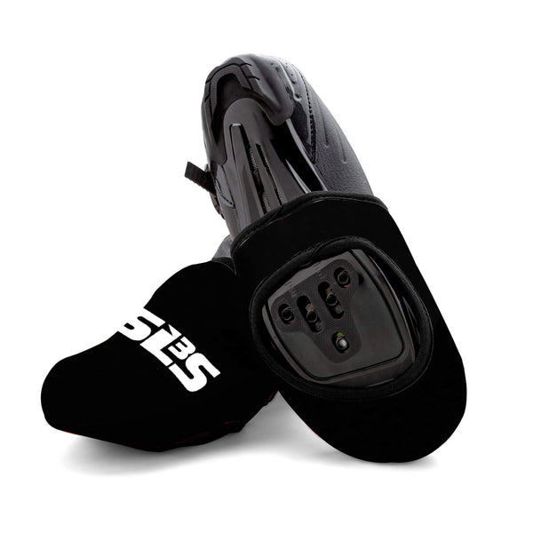 A pair of black cycling toe covers with cycling shoes